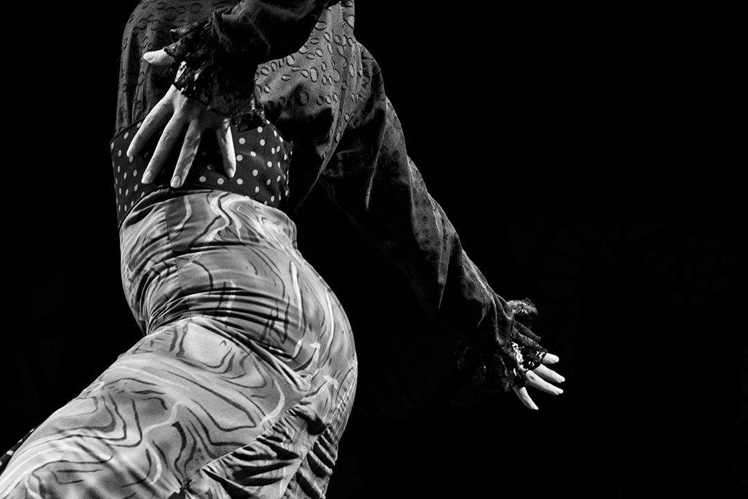 Una bailarina arquea el cuerpo con un brazo extendido.